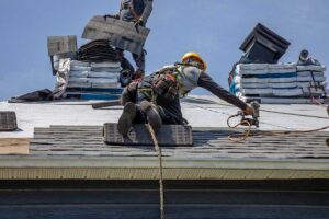 Gutters carry rainwater from a shingled roof through downspouts beside a two-story home.